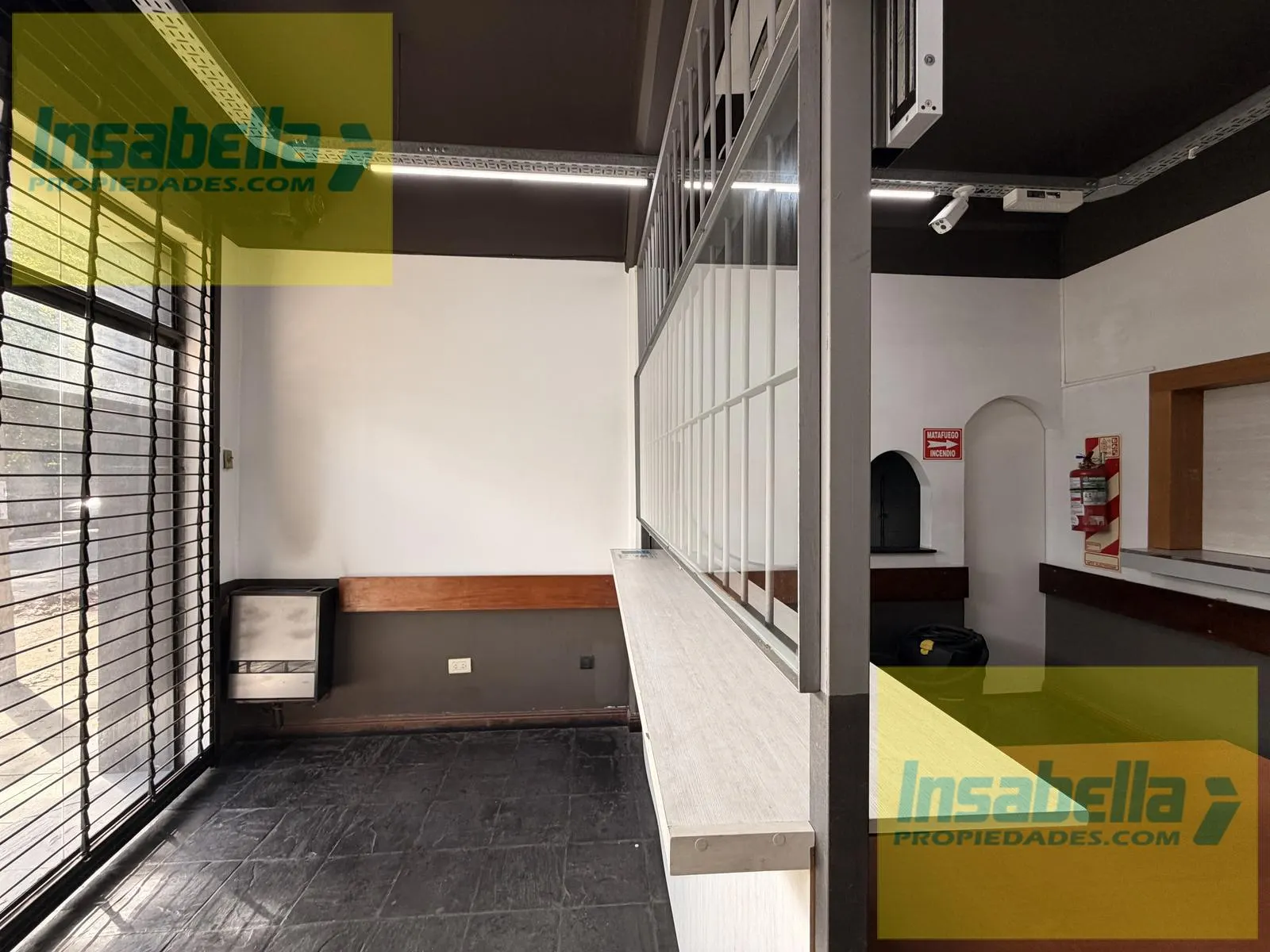 Salón de atención al público al frente del local, con mampara baja y piso de pizarra