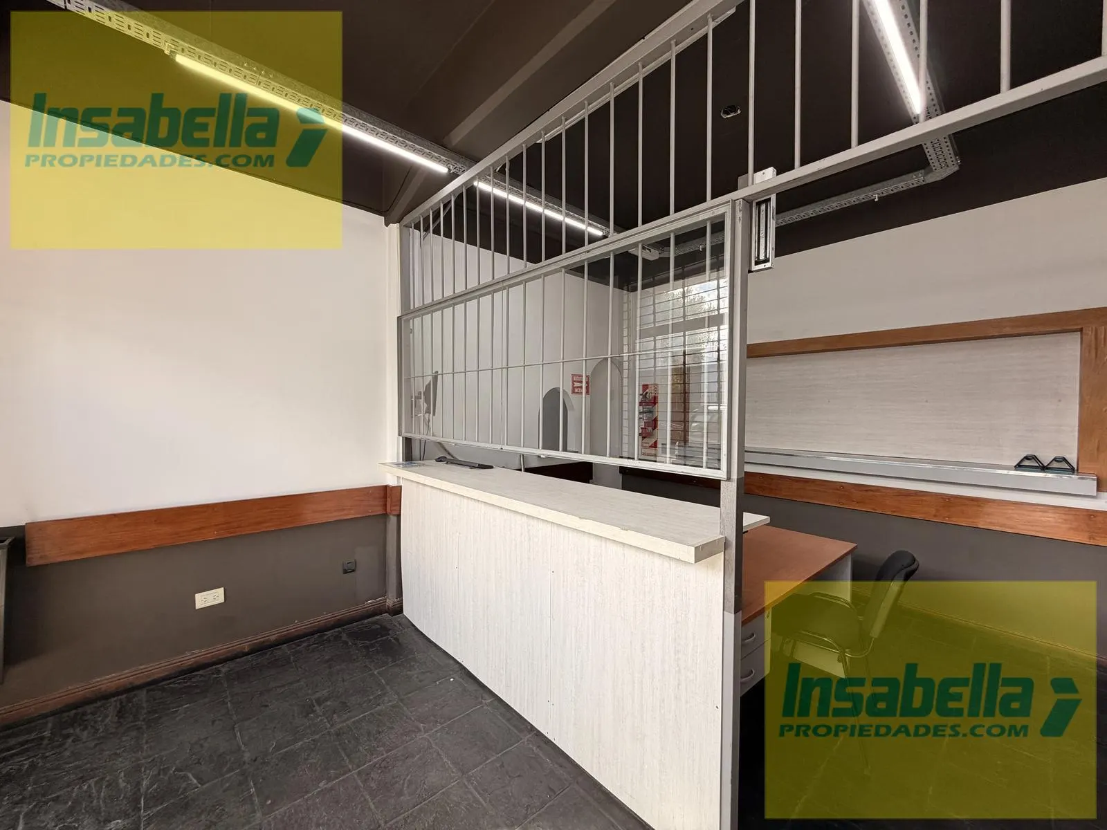 Mostrador de recepción con mampara alta separando atención de oficina