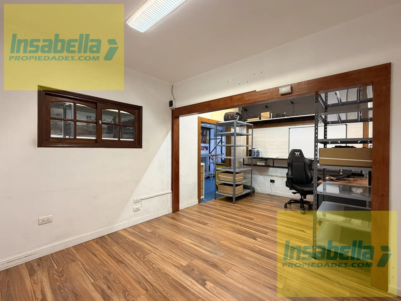 Otra vista de la oficina privada con piso de madera y estantería auxiliar