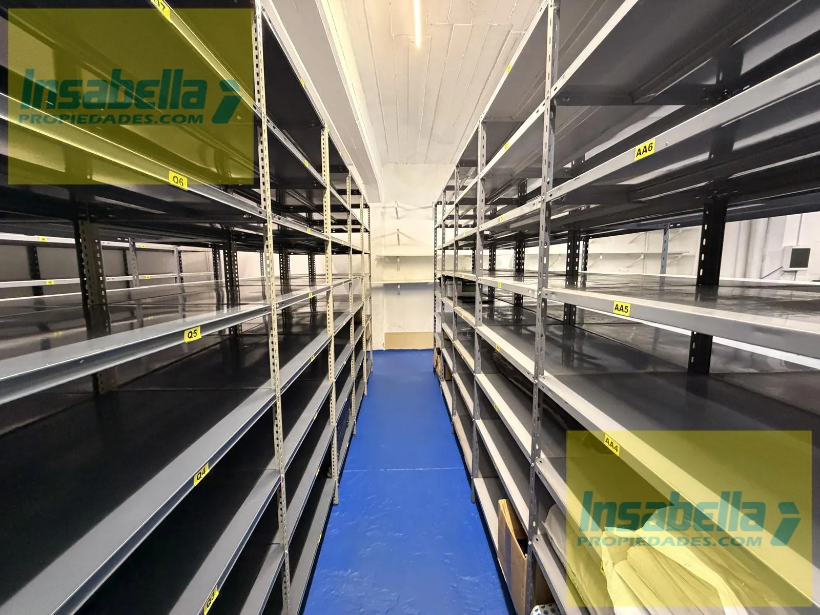 Pasillo central entre estanterías numeradas del depósito